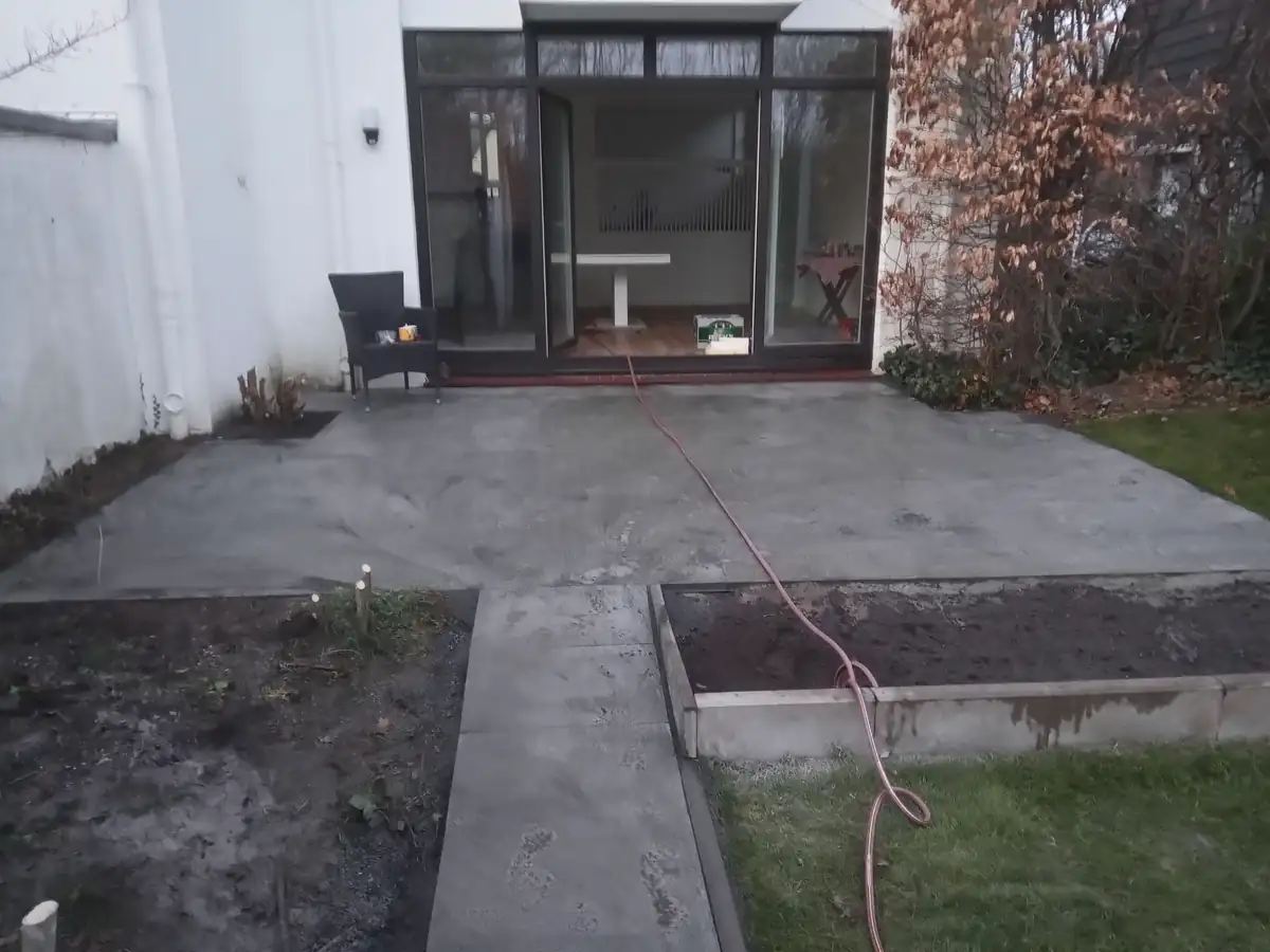 Neue Terrassenfläche mit Weg und eingefassten Beeten vor einer Glasfront