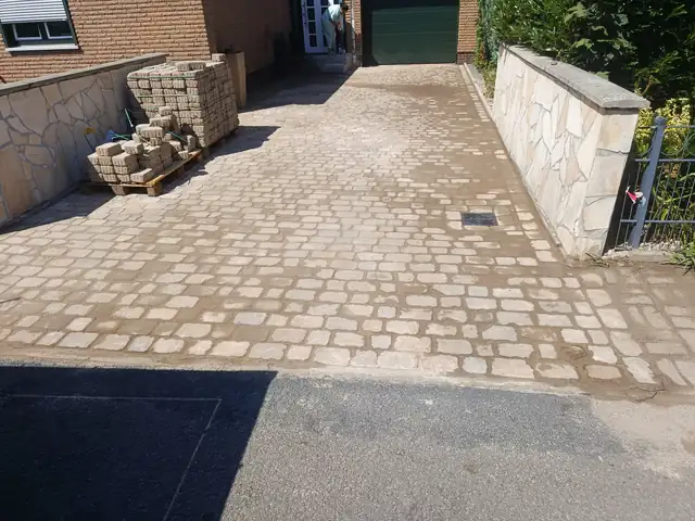 Gepflasterte Einfahrt zwischen Natursteinmauern